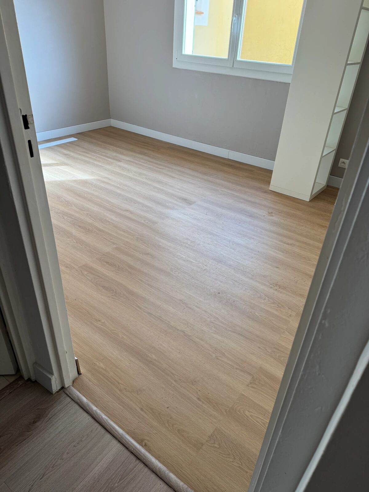 Chambre rénovée avec parquet stratifié, plinthes et peinture neuve