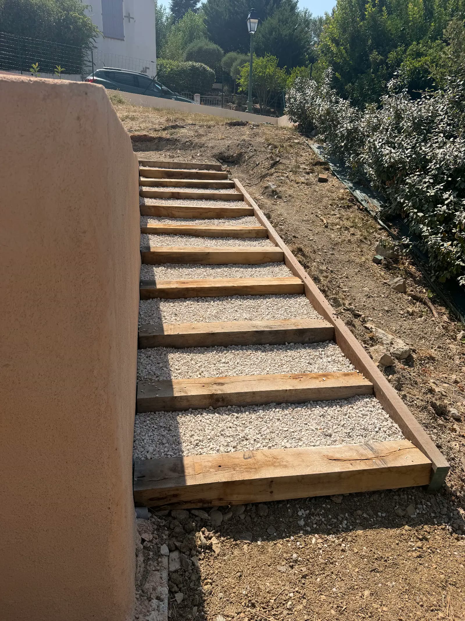 Escalier extérieur en traverses de bois et gravier blanc sur terrain en pente